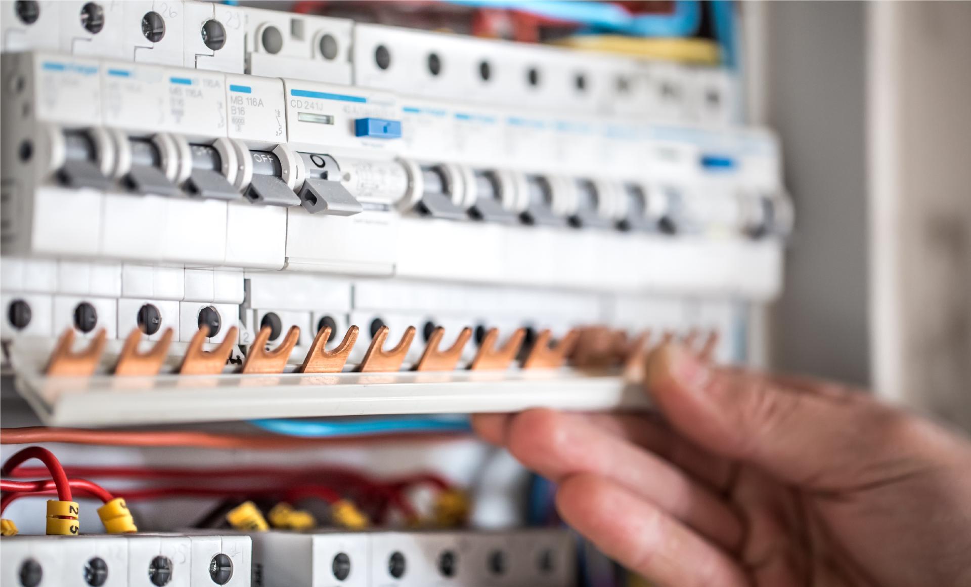 Man electrical technician working switchboard with fuses installation connection electrical equipment close up
